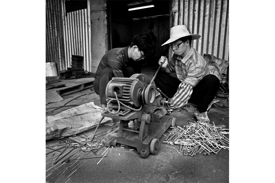 Grinding metal tubing pieces manually to factory specifications.