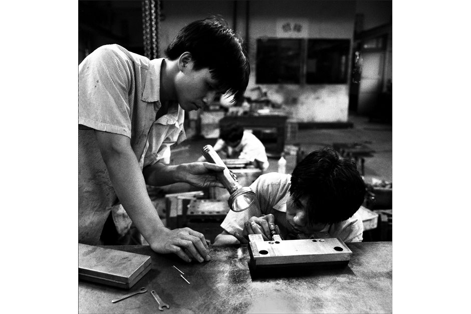 Adjusting a plastic parts mold with the assistance of a flashlight.