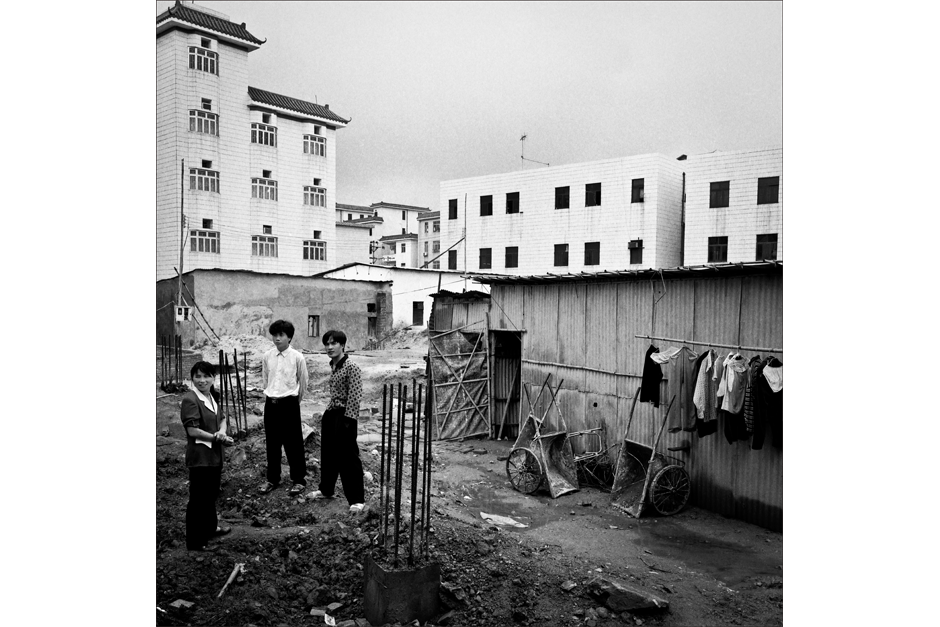 Corrugated tin houses, foreground, were being replaced by new construction of factory buildings and residential complexes.