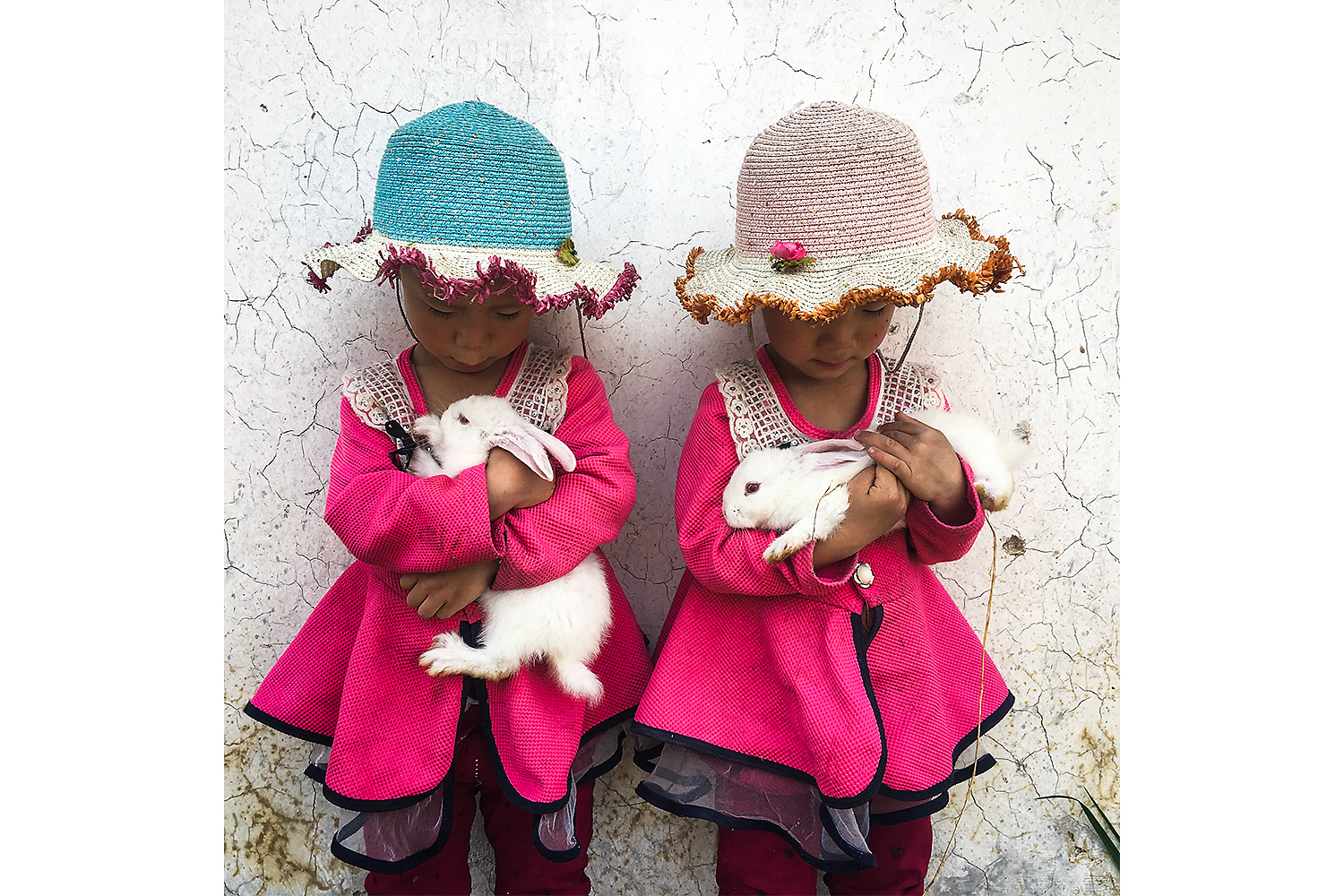 Three-year-old twin sisters Xinran and Xinyi play with their pet rabbits outside their home in Taizicheng Village, Hebei province. Photo by Yan Cong @yancongphoto