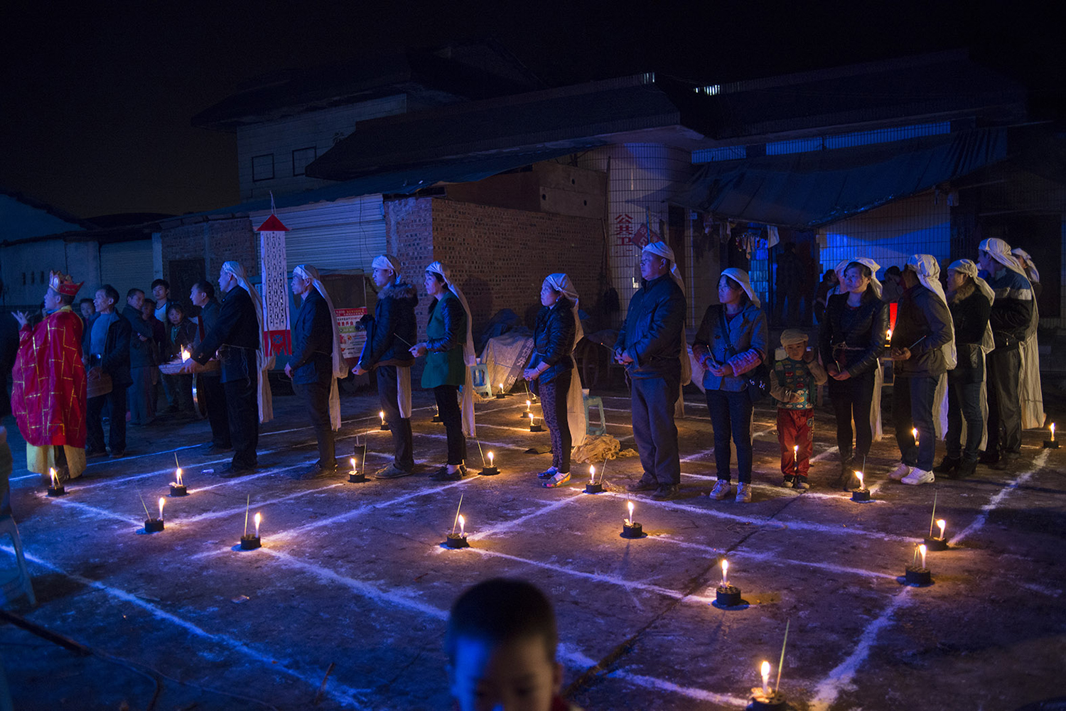 A line of family members holding burning incense follow a monk as a ritual to send the departed onto the path to heaven, November 11, 2014.