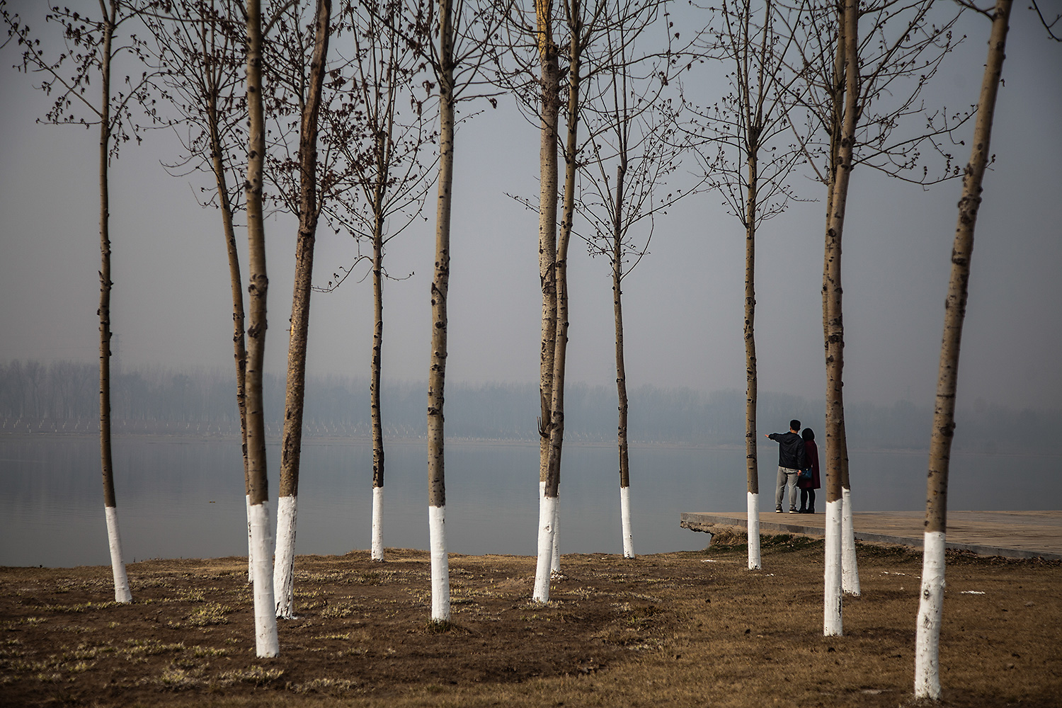 On the bank of the Chaobai River in Tianjin, retired firefighter Zhang Mengfan stands with Zhou Junqing, the mother of Jiang Shilei, who died in a massive chemical factory explosion in the city in 2015, one week before Jiang was supposed to be married. Following the explosion, Zhang embarked on a journey across China, visiting several of the families of the 110 firefighters killed in the explosion, eight of whom were his own colleagues. Photo by Zhou Na @zhounaphoto