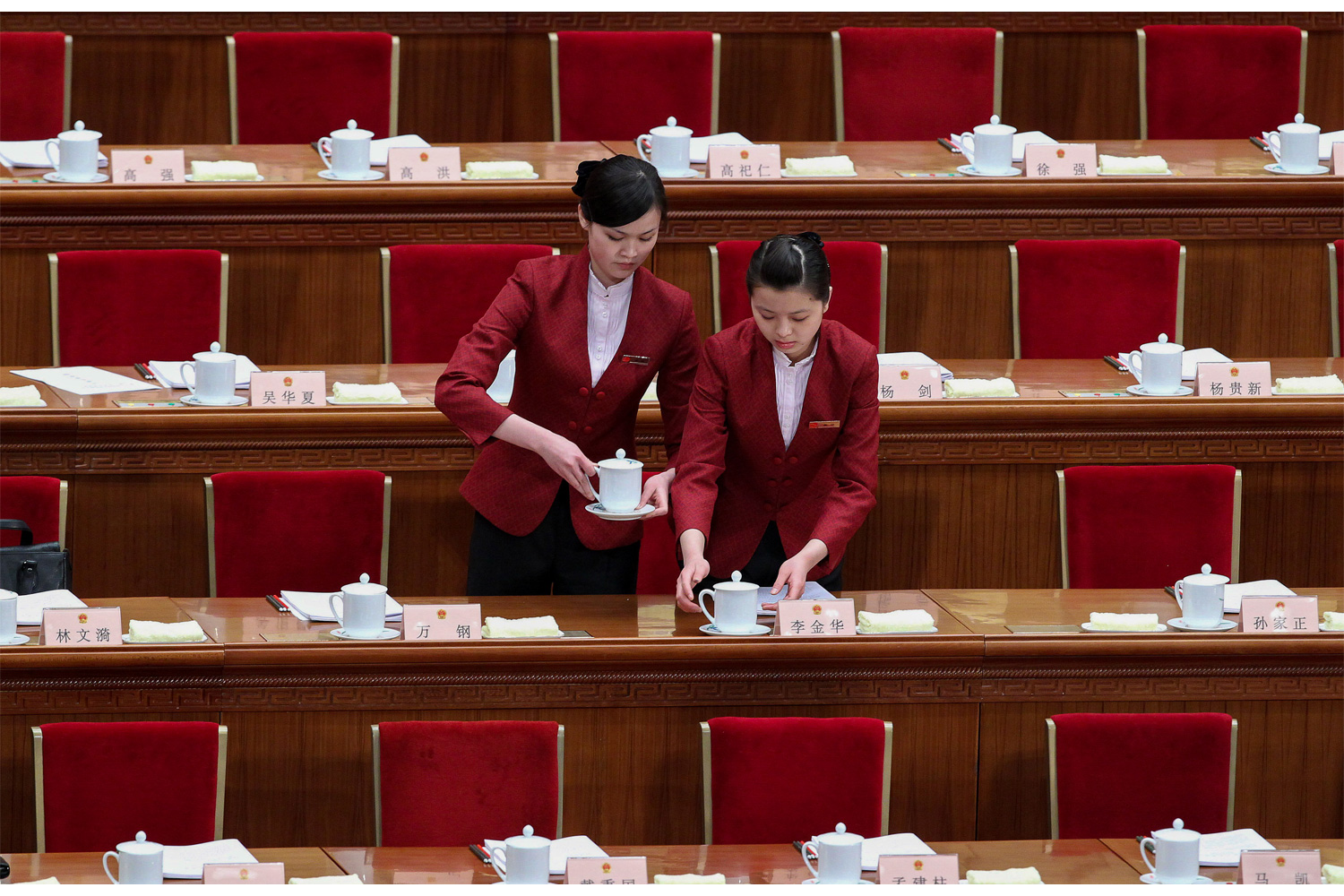 Two waitresses arrange tea cups at each parliament member’s seat in the Great Hall of the People, March 5, 2010, for the Third Session of the 11th National People’s Congress.
