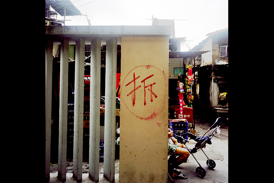 The Chinese character <em>chai</em>, meaning “to demolish,” marks the wall at the entrance to the neighborhood of Lane 1289 West Yan’an Road, Shanghai, July 31, 2009. The government usually marks buildings and neighborhoods slated for demolition with this character; in this case, however, it was the residents who painted it, with the hope that an urban renewal project would finally reach them and they would receive money to move out. Officials from the Neighborhood Committee (<em>jiedao banshi chu</em>) routinely erased the marking, only to see it repainted by the residents soon after.