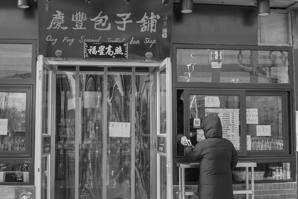 A customer orders food through a window at Qingfeng Baozi restaurant on Xuanwumenwai Avenue, February 18, 2020.