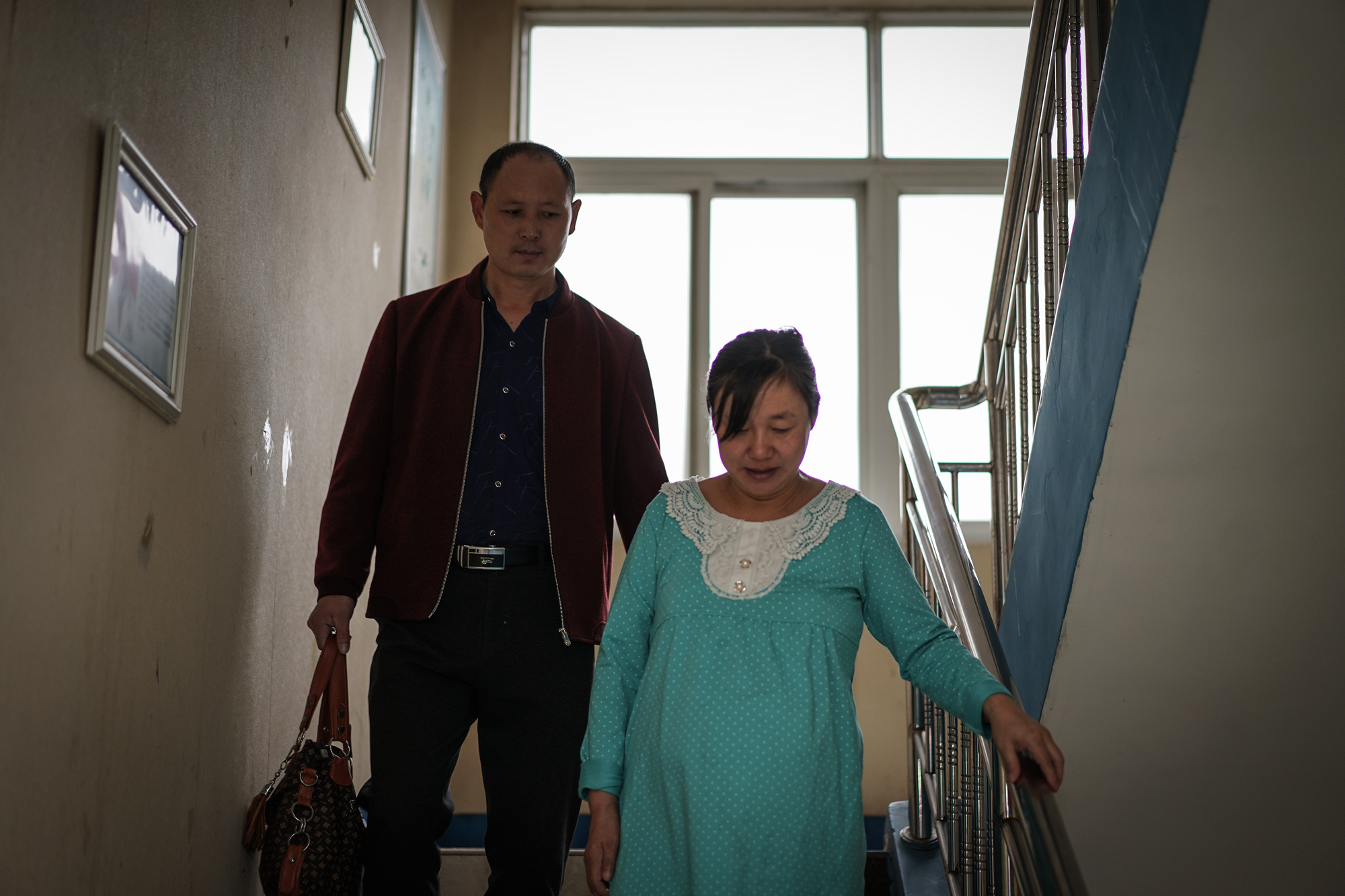 Fangguo watches Zhiying carefully walking downstairs at the hospital, in Wuhan, October 3, 2017. Even though carrying twins meant Zhiying and her babies faced higher health risks during pregnancy, they specifically tried to have twins when they started IVF because they hoped the children could take care of each other after the parents pass away.