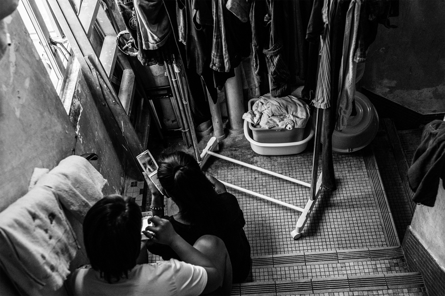 Sunarwi, left, and Kuryati, Indonesian domestic workers, take a break in the back staircase of the shelter. Most Indonesian workers complain that they are underpaid. According to Bethune House staff, Indonesians are paid less than other nationalities, and their income often falls below the minimum allowable wage level set by the Hong Kong government.