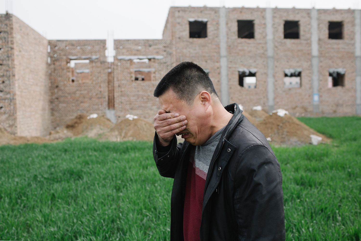 April 10, 50-year-old Zhao, owner of a shoe factory, covers his face to hide tears while discussing his worries about the future, in Anxin county, Hebei province. The Chinese central government announced the establishment of the Xiong’an New District on April 1. The district, designed to become a hub of economic development, encompasses the counties of Xiongxian, Anxin, and Rongcheng in Hebei. Many locals have feared their small businesses will be displaced by newcomers. (Wu Huiyuan/Sixth Tone)