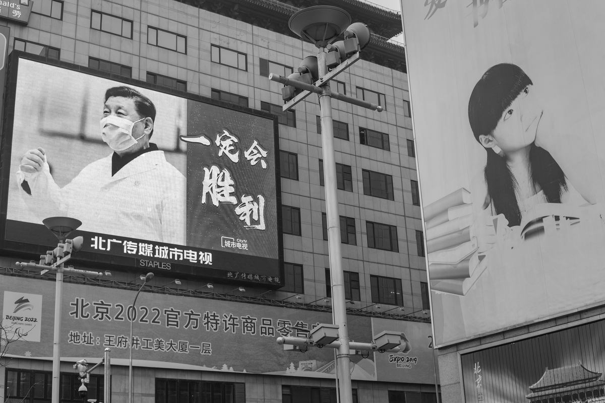 A billboard on Wangfujing Street shows a picture of Xi Jinping wearing a mask and lab coat, and the message “We will win,” February 20, 2020.