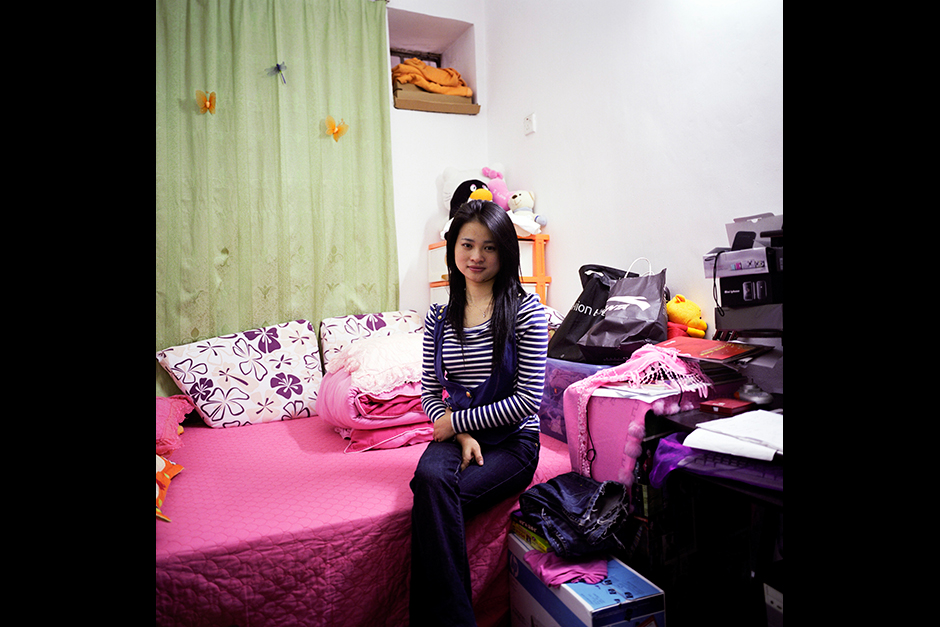 Ms. Zhou Hui poses for a portrait in her bedroom in Xiangxi Village. She paid US$150 in rent per month, for an apartment that she shared with a roommate. Ms. Zhou, who was born in 1986, is young, single, and moved to Shenzhen from a rural village in Hunan province in 2002. She was working in a luxury spa, saving most of her income with the hope of purchasing an apartment with her sister one day. However, her savings likely will not catch up to the pace of the rising cost of housing in Shenzhen, where today prices have reached US$4,800 per square meter in Ms. Zhou’s neighborhood.