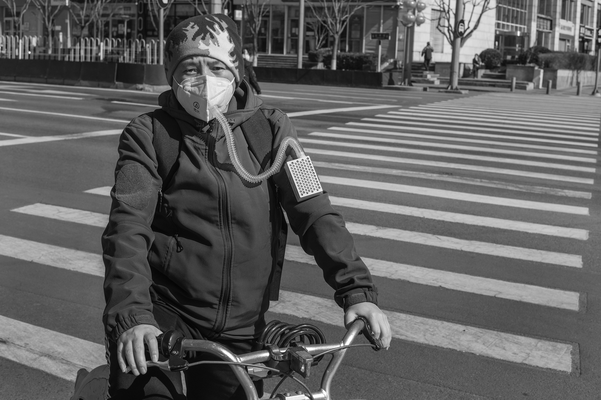 A man breathes through a device intended to filter air, on Taiping Street, February 18, 2020.