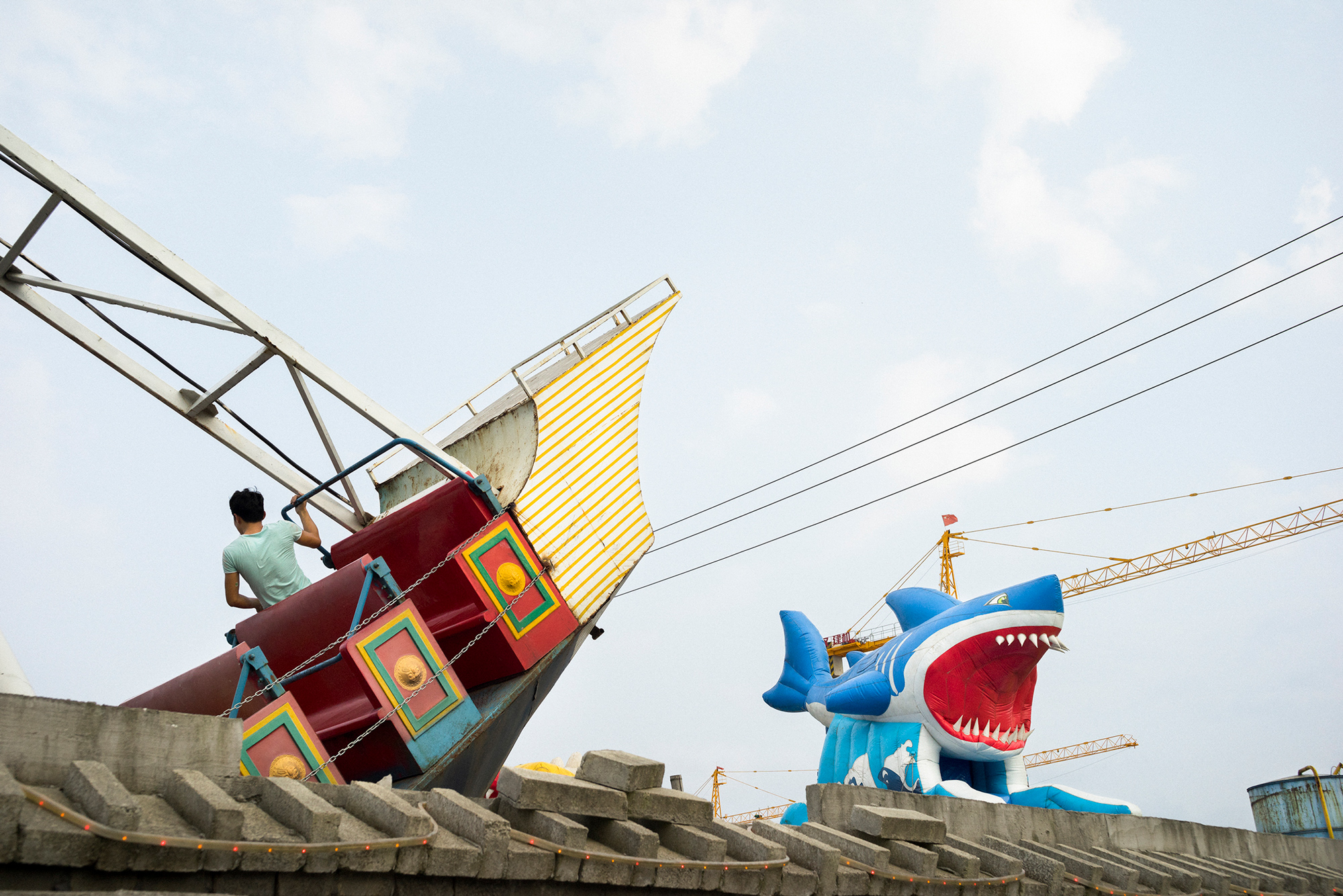 A man enjoys a ship-themed ride at a small amusement park on the former site of a farm in Feiyun, September 8, 2014. A residential complex is under construction beside the park. 
