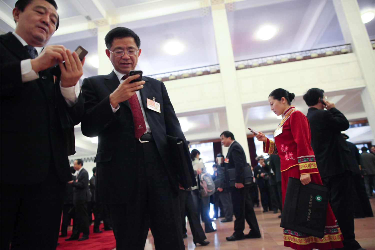 NPC members check their mobile phones, March 8, 2011, at the Great Hall of the People.
