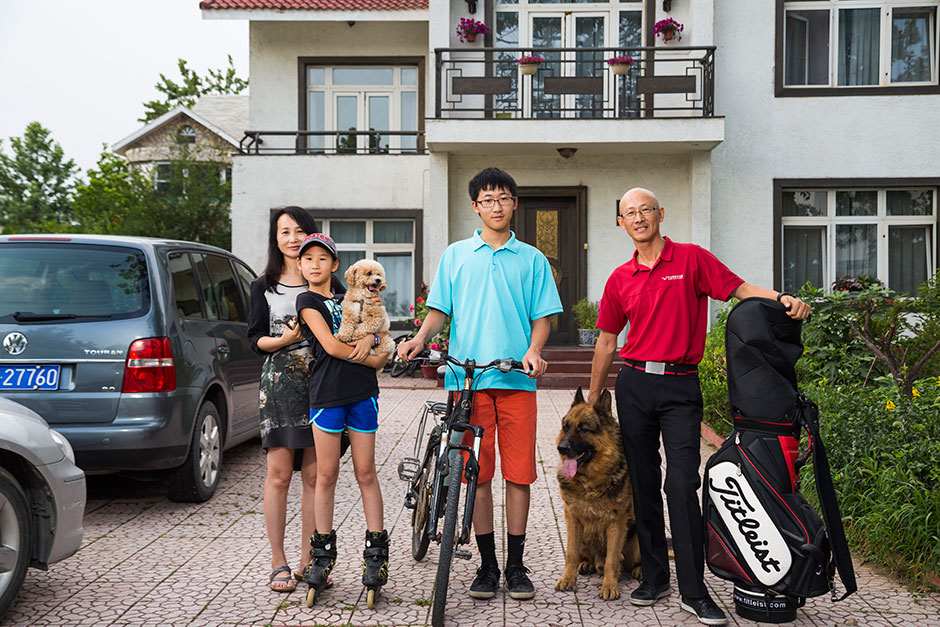 Wayne Ma, right, founder of Vision Golf Academy, stands with his family outside their million-dollar home in the suburbs of Beijing.