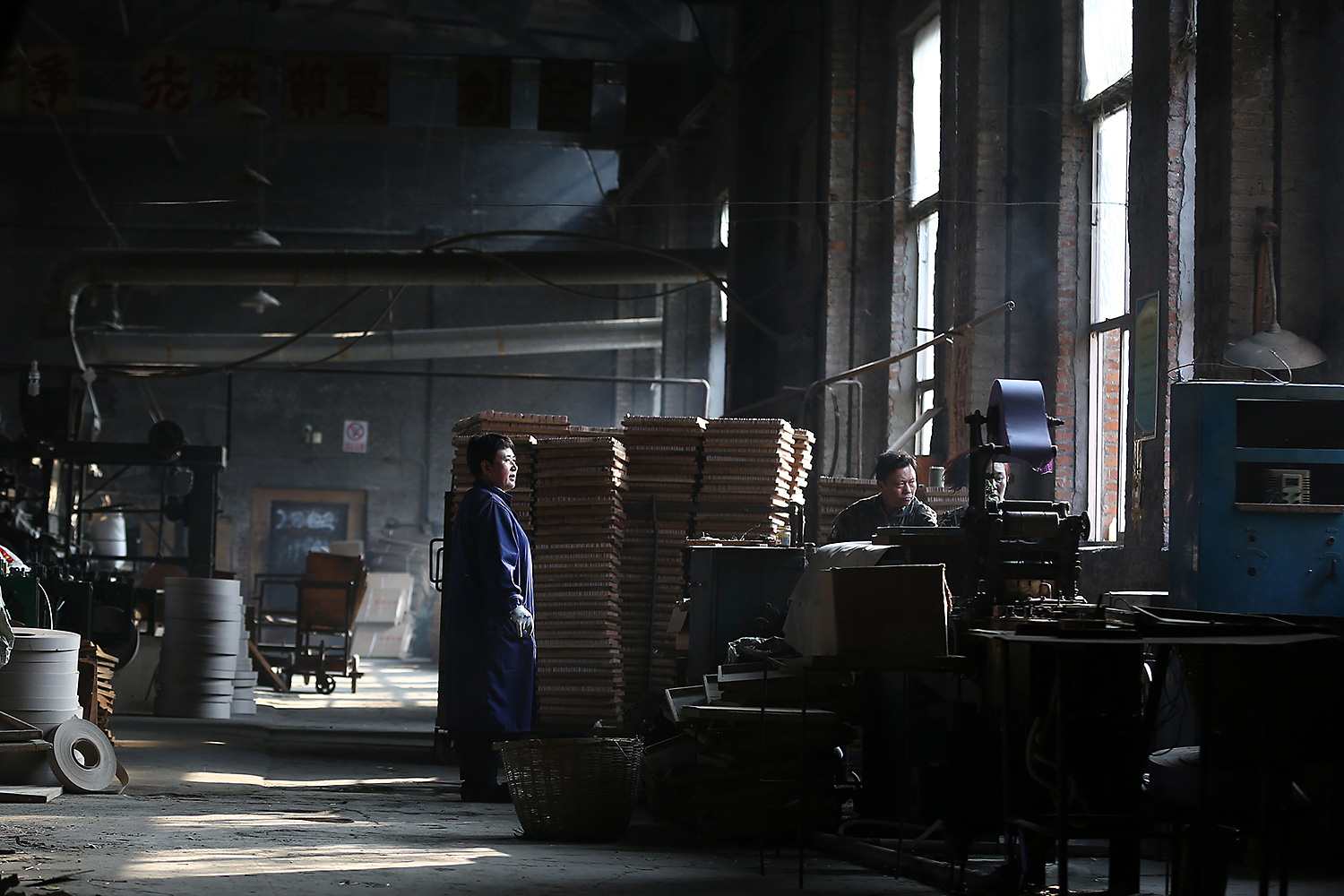 Factory Director Chu Junping, right, works with the old machines. With the factory’s heyday long over, Chu says his business relies on old customers to keep it afloat.