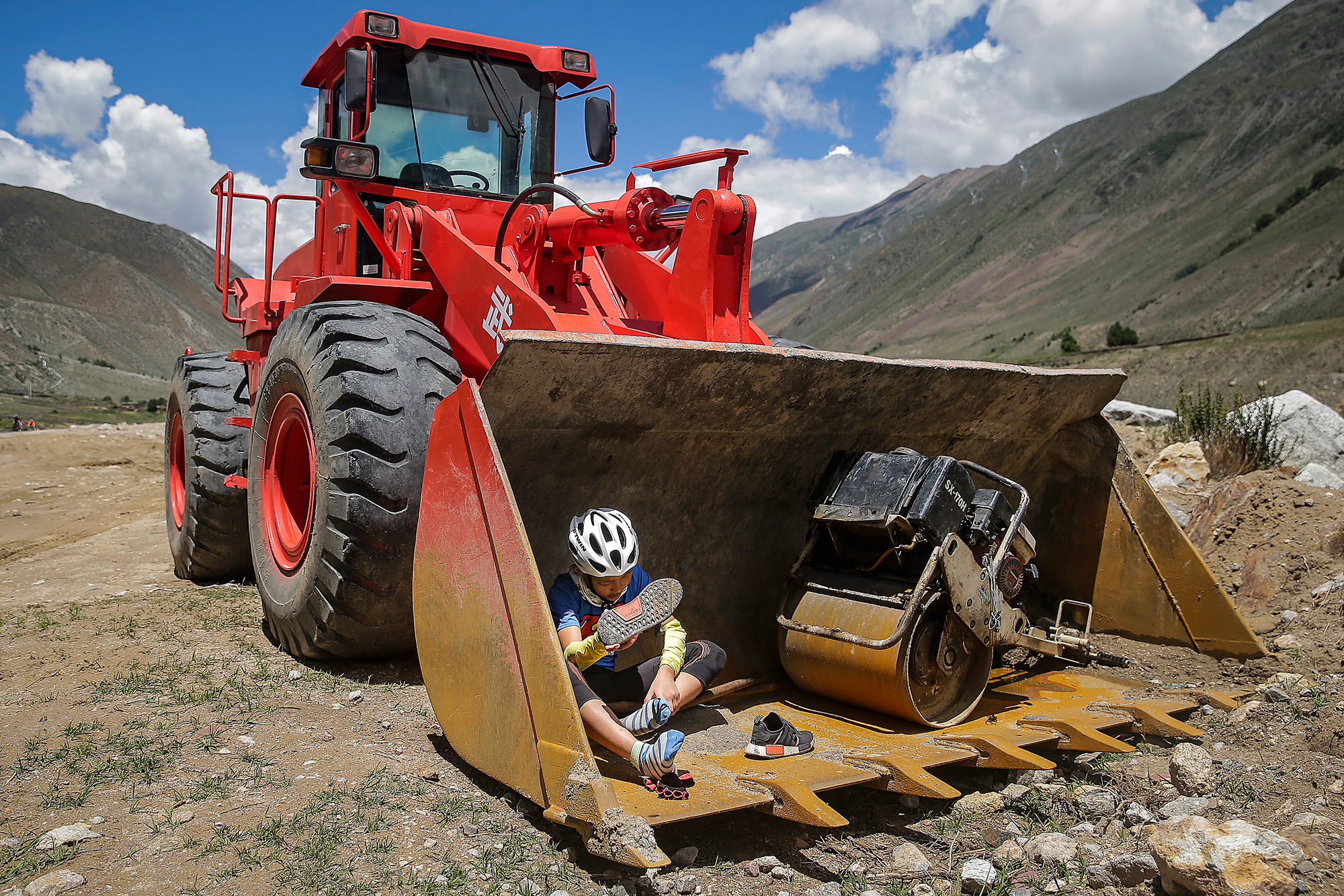 Runxi finds some shade to adjust his sneakers, in Baxoi county, Qamdo, July 30.