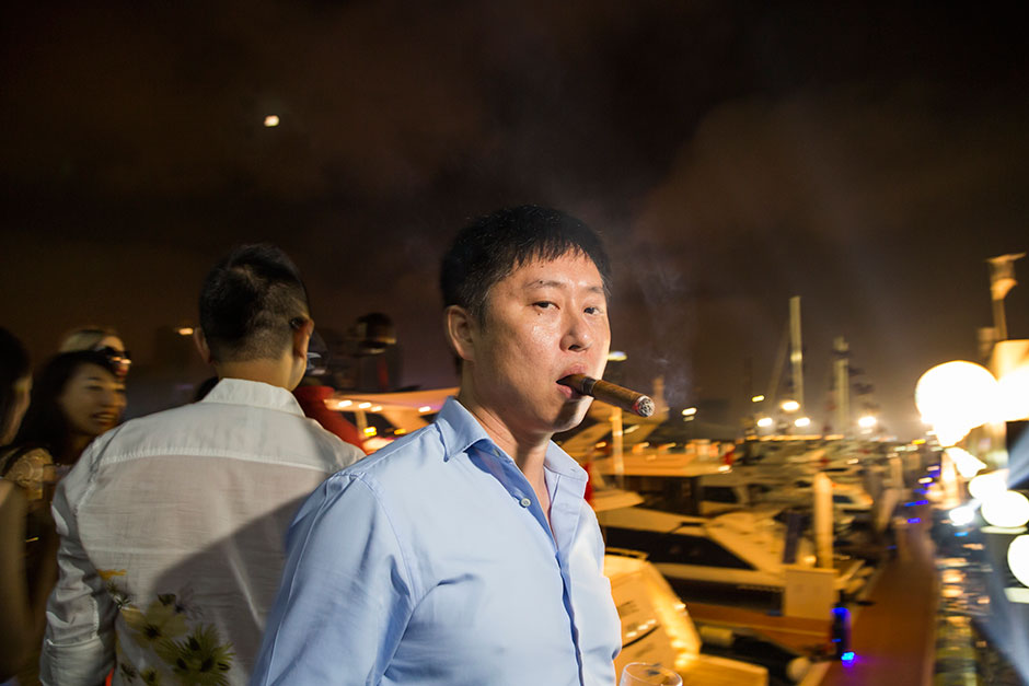 A vendor of high-end vintage cigars smokes some of his product at a private Sanlorenzo cocktail party in Dalian.