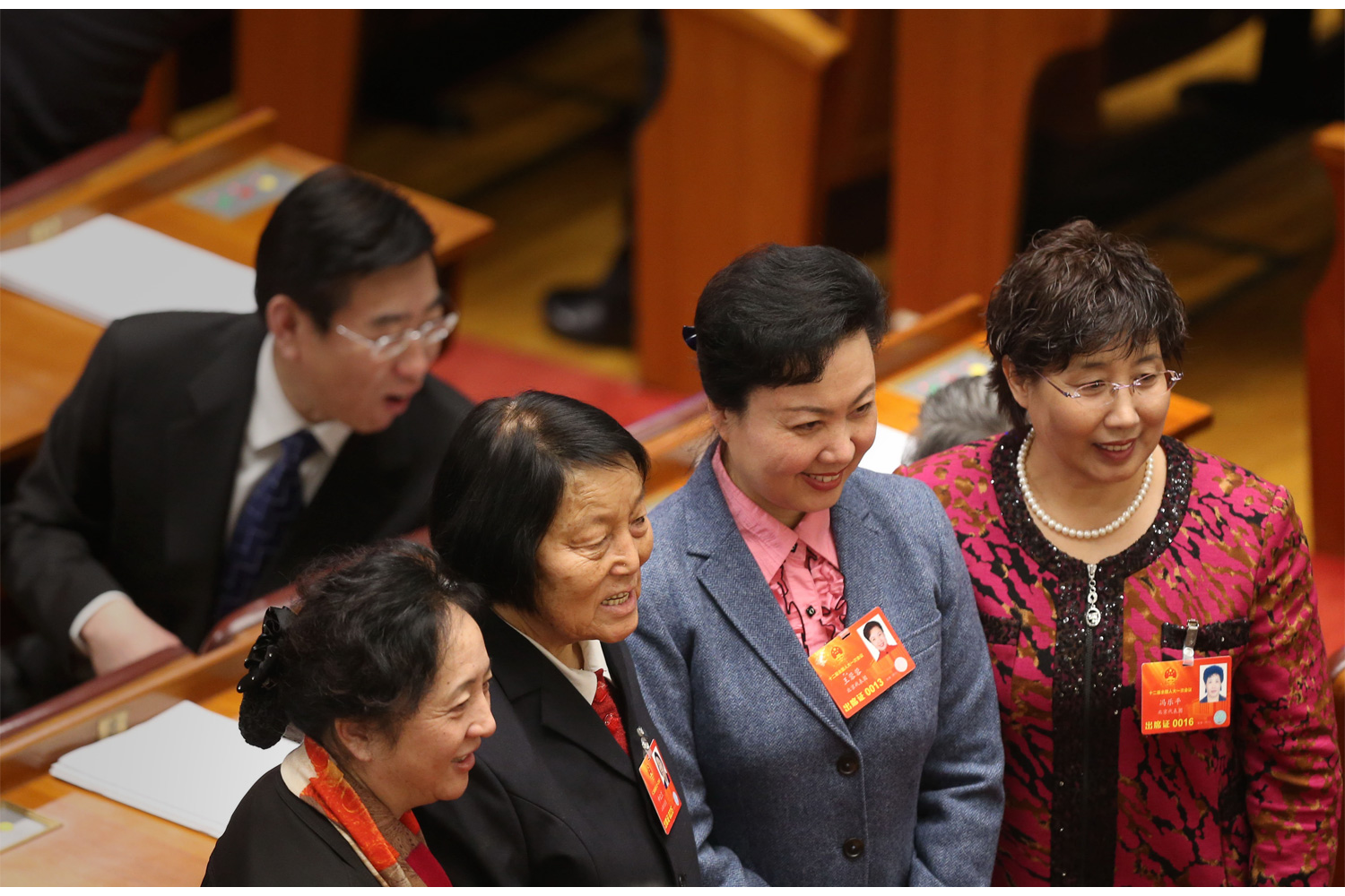 A deputy in ethnic clothing, bottom left, stands for a photo with other female deputies before the start of meetings, March 5, 2013, in the Great Hall of the People.