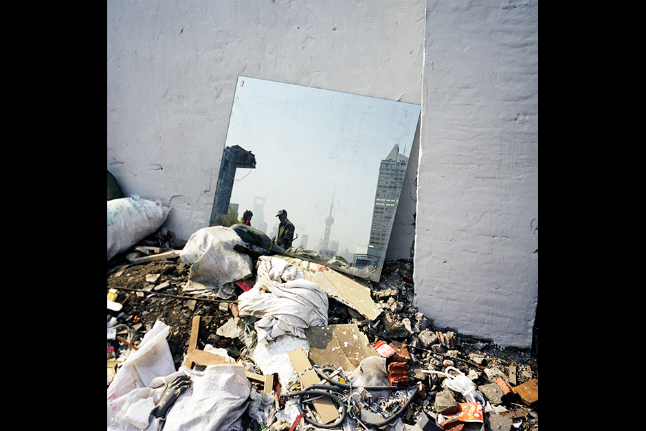 The skyline of Shanghai’s Lujiazui Financial Center in Pudong District is reflected by a mirror lying in a demolition site, January 2010.