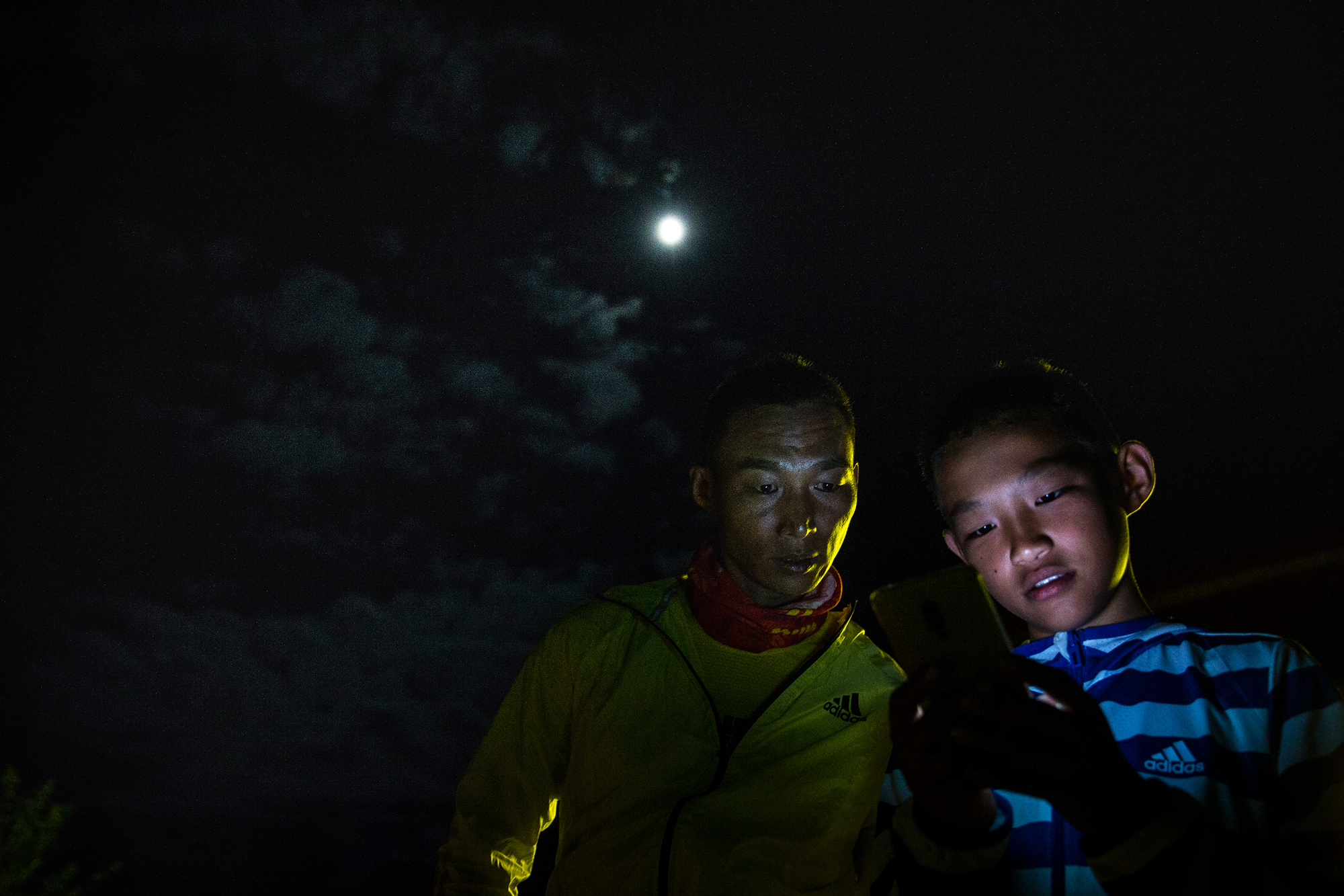 Runxi uses his dad’s phone to try to find a hotel for the night, in Guxiang Village of Nyingchi city, Tibet, August 1.