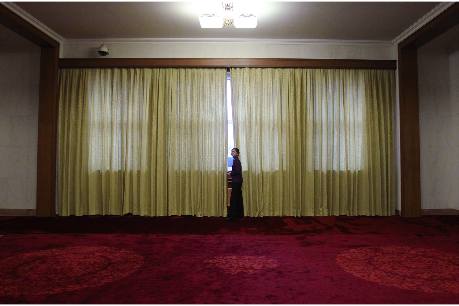 A waitress stands by a window in the corridor outside the Great Hall of the People, March 10, 2011, during the afternoon of the Fourth Session of the 11th CPPCC.