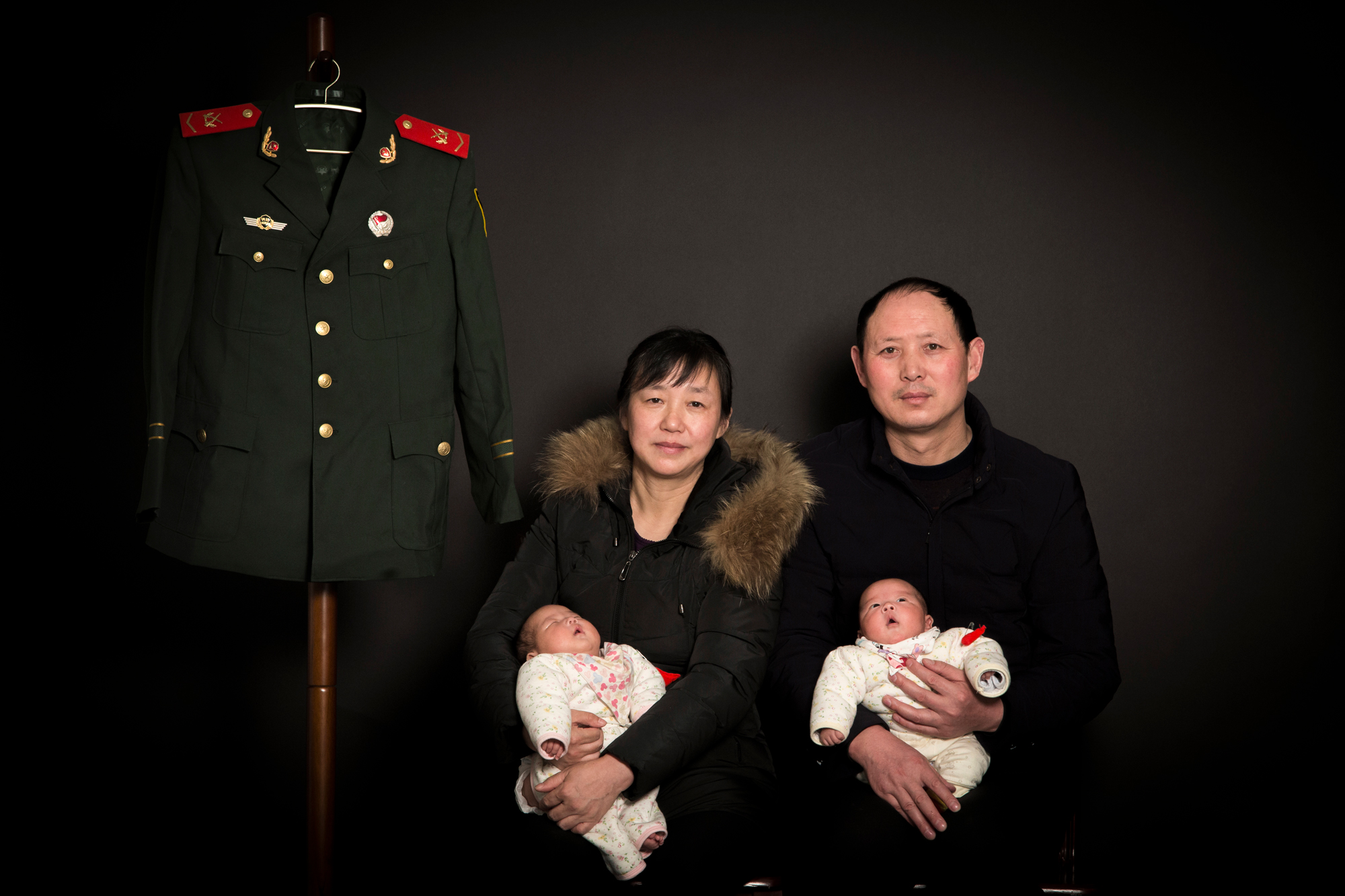 Zhiying and Fangguo hold the twin babies to pose for a family photo with Ti’s military uniform, at their home in Suizhou, February 10, 2018.
