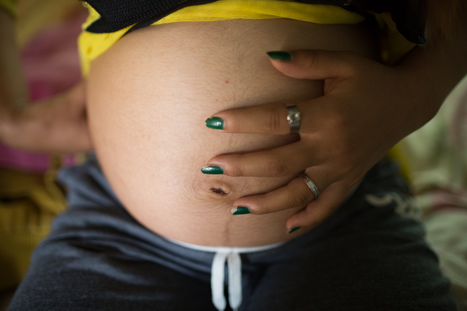 Jie touches her belly at the start of her third trimester at her home. She was 13 years old and her husband 18 when this picture was taken. They met during the Spring Festival and were married three months later. After the wedding, Jie quit school. She didn’t finish the fifth grade. 