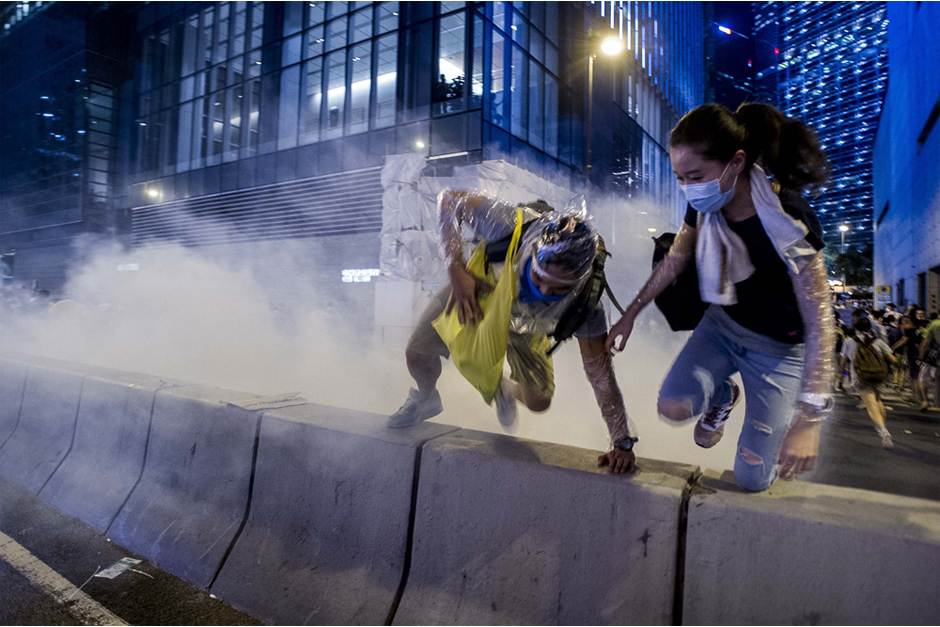 Pro-democracy demonstrators jump a barrier to escape a cloud of tear gas. (Photo by Xaume Olleros /AFP/Getty Images)