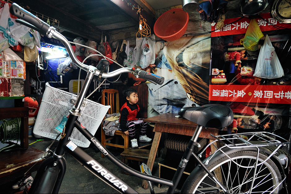 Wuwucun families paper their walls with advertising posters to keep out drafts and smells.  Xu Huali bought a new bicycle for the half-hour ride she takes with several other women to and from the factory.  Sundays she parks it in her next-door neighbor’s home because she and her husband don’t have enough space in their smaller home. 
