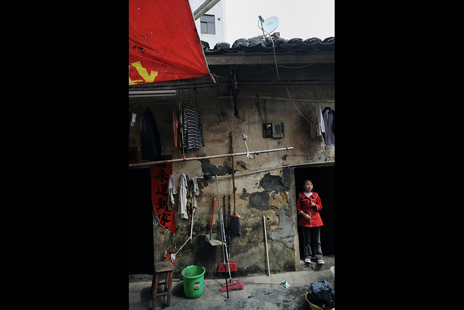 Wearing her holiday best, a girl stands in the doorway of her Wuwucun home.