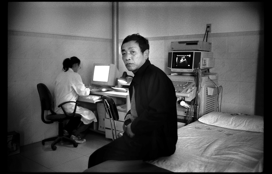 Shi Dage waits on a hospital bed to receive a liver exam. Without appropriate monitoring or treatment, one in four people infected with chronic hepatitis B will die from liver cancer or liver failure. Henan, China