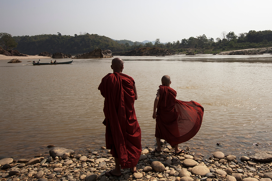 Monks stand at the edge of the confluence waters of the Mali and N’Mai Rivers.