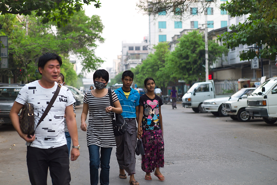Mainland Chinese walk on the streets of Mandalay, their clothing and demeanor identifying them as foreign.