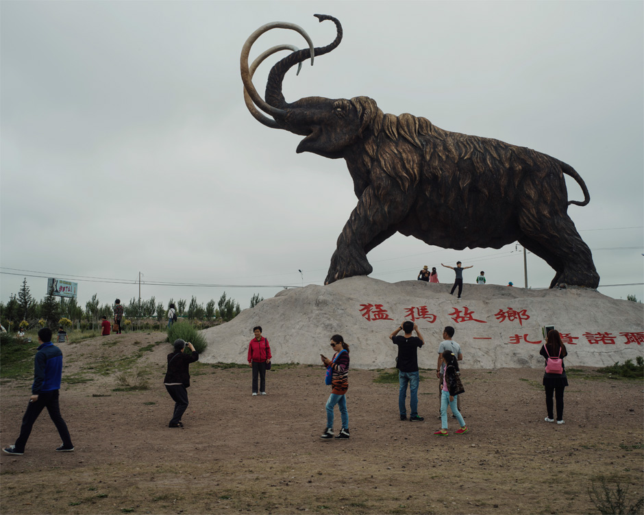 Tourists visit a wooly mammoth statue, built to commemorate a fossil discovery, in Mammoth Park in the Jalainur district of Manzhouli.