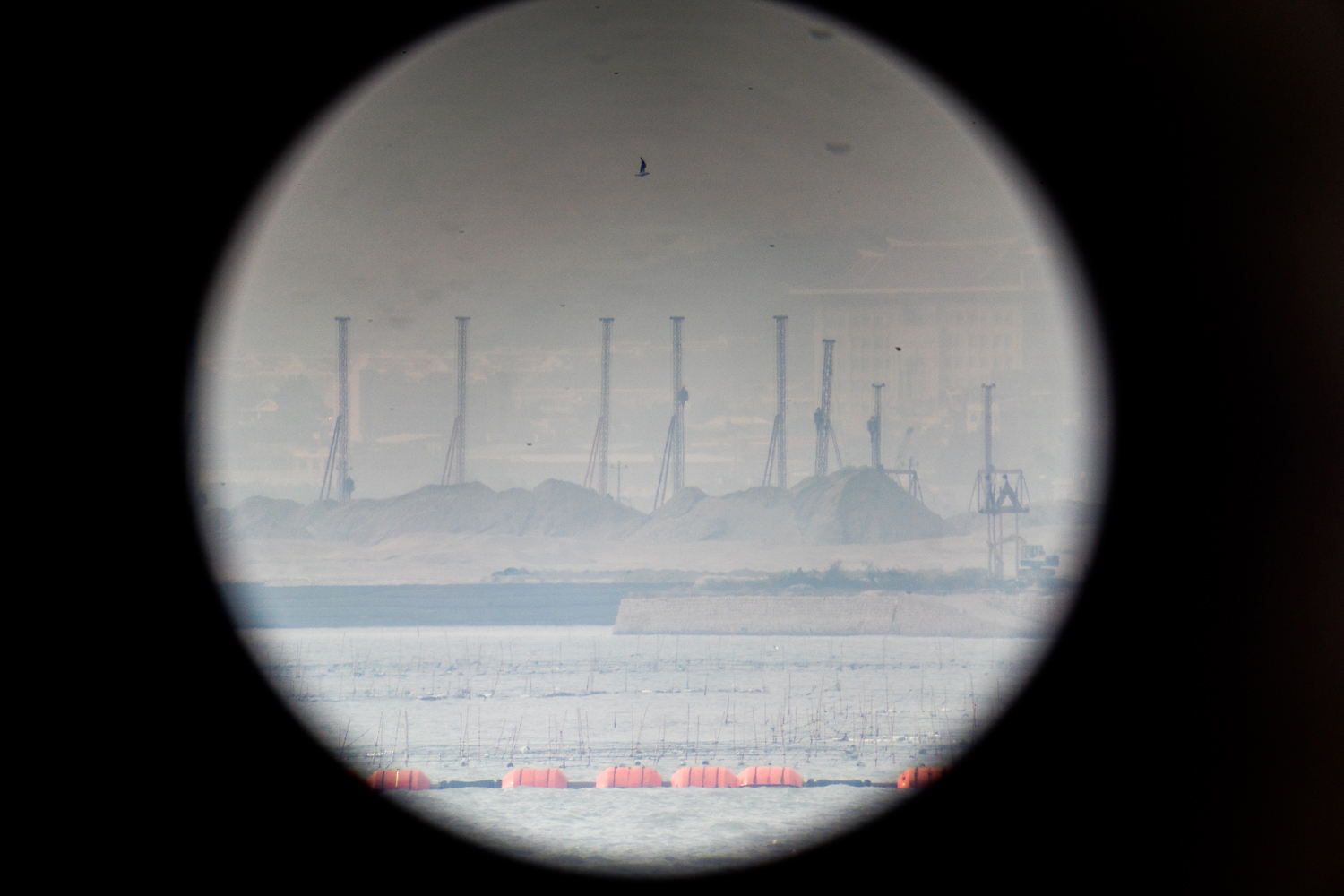 Viewed through binoculars from the Mashan Observation Station on Kinmen, pile drivers rise above sand dunes on China’s Dadeng Island, the closest point in mainland China to Kinmen, and the proposed site of nearby Xiamen’s new airport.