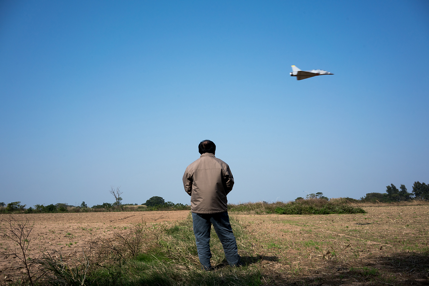 A miniature, battery-operated Dassault Mirage 2000 fighter jet—a scale model of the ones the Taiwan Air Force uses—zooms past an open field in Kinmen. Piloting it is Chen Minghan, an air conditioner repair man originally from mainland Taiwan. He said, ‘People ask me if it’s good to reunite with mainland China. I say it’s now not good but in the future it might be good. There is a better quality of life and more freedom here, even if we are more backward compared to China. Their smog is blowing over there. China is so big and Taiwan is so small. If every person in China spat, it would flood all of Taiwan!’