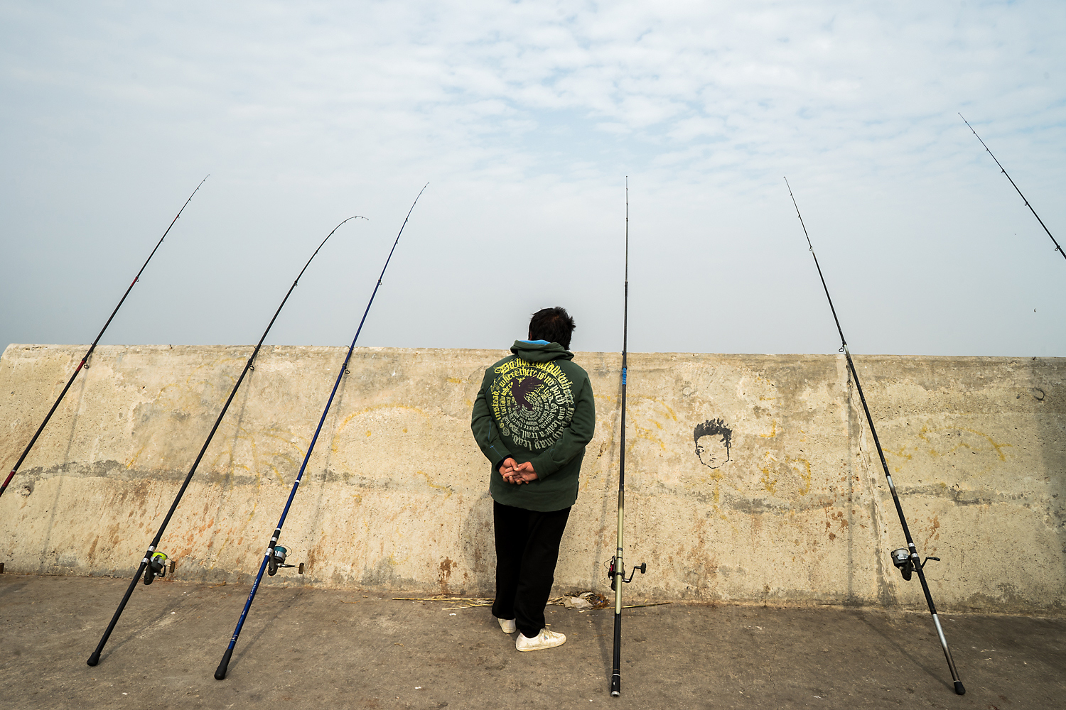 An angler waits for a bite at an embankment near the Shuitou ferry terminal. The embankment was built alongside the ferry terminal and lighthouses on reclaimed land and part of what was formerly a fishing village. Some local residents from the village protested the development, which made them lose their natural port and fishing livelihood and also harmed the habitat of the horseshoe crab.