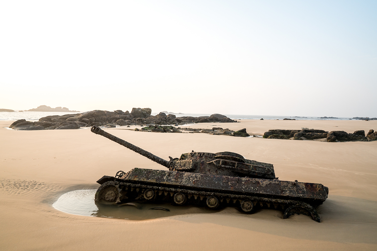 A military tank, half buried in the sand on a beach, is visible at low tide in Kinmen. The island was managed as a military base from 1949 until 1992, when martial law was lifted. KMT leader Chiang Kai-shek stationed a significant portion of his army on Kinmen, planning to retake mainland China from there. At the height of the Cold War, as many as 100,000 soldiers were barracked on Kinmen, outnumbering civilians. Today, there are only about 3,000 troops left on the island.