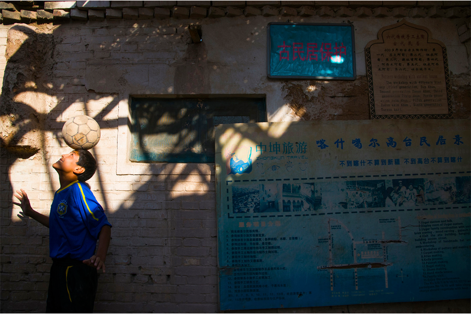 In the old city of Kashgar, a descendant of seven generations of Uighur potters balances a soccer ball in the alleyway in front of his house. The “beautiful game” first came to Xinjiang province in the nineteenth century.