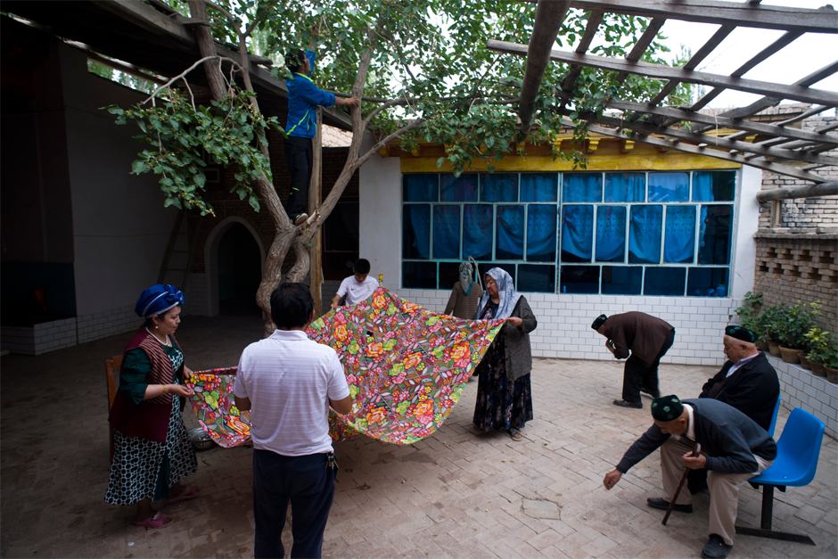 In Memet Zunun’s courtyard, family members pick up mulberries that his grandson, Ekber, standing in the tree, has shaken loose. Ekber, a fourth-generation soccer maven, was a star player on an Artux team sponsored by local businessmen. Now he teaches physical education at Iksak Elementary School.