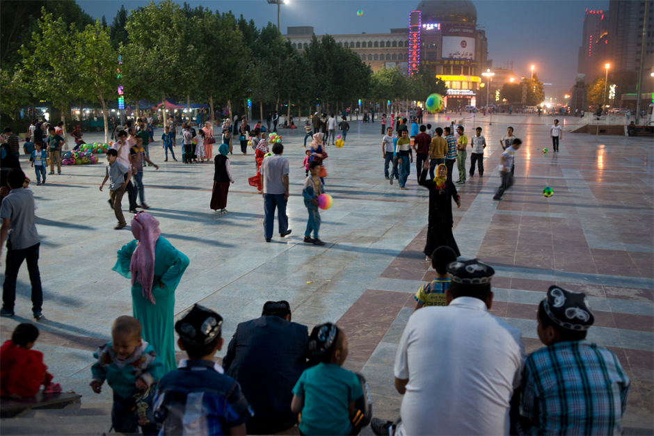 In the central plaza of Hotan city, people of all ages play soccer as dusk falls.