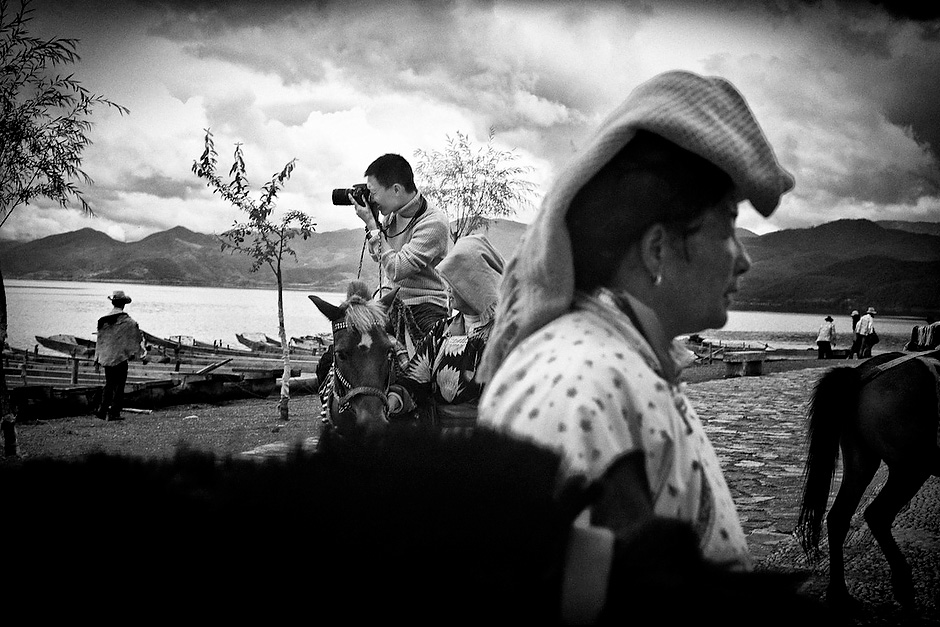 Tourists take pony rides led by Mosuo women at Lugu Lake. Yunnan, China.