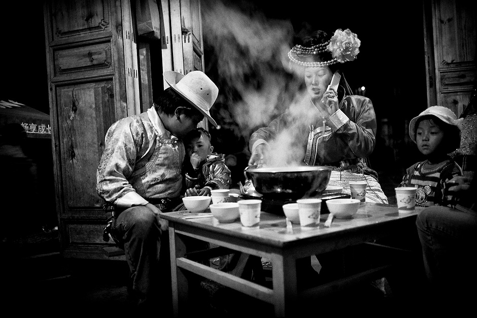 Zha Ba and Na Zhu have supper with their daughter, La Mu, and Na Zhu’s family after performing at the Mosuo Cauldron Fire Evening. Although they practice “walking marriage,” Zha Ba gets to see his daughter frequently, unlike most Mosuo men in previous generations. Luoshui, Yunnan, China.