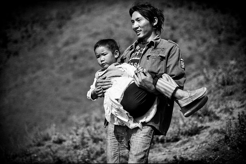 Su Na Dorje, 26, takes his two nieces up the hill to the village shrine to worship. As the maternal uncle, Su Na has to play the role of father to the two girls, Zhi Ma La Zu, 8, and Zha Xi Yi Zong, 4. In the matrilineal Mosuo culture, uncles serve as fathers to keep the family structure intact. Women rule the roost, while their brothers practice “walking marriage.” The men are not allowed to set up their own families, but instead stay within their extended families as shared father figures. Aguwa, Yunnan, China.
