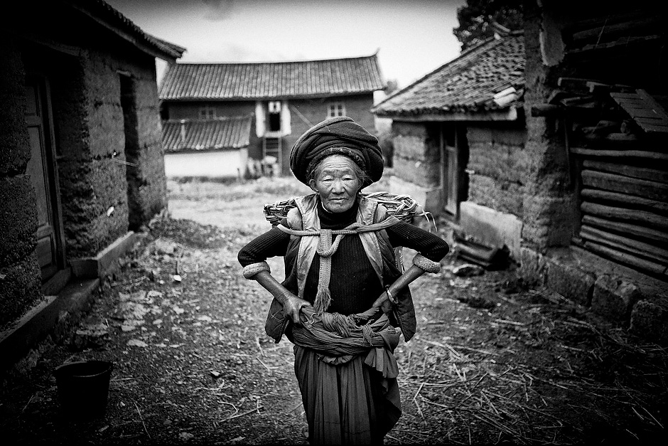 Cier Zhima, 73, the matriarch of a Mosuo household, poses for a picture before heading off once again for the fields. Aguwa, Yunnan, China.