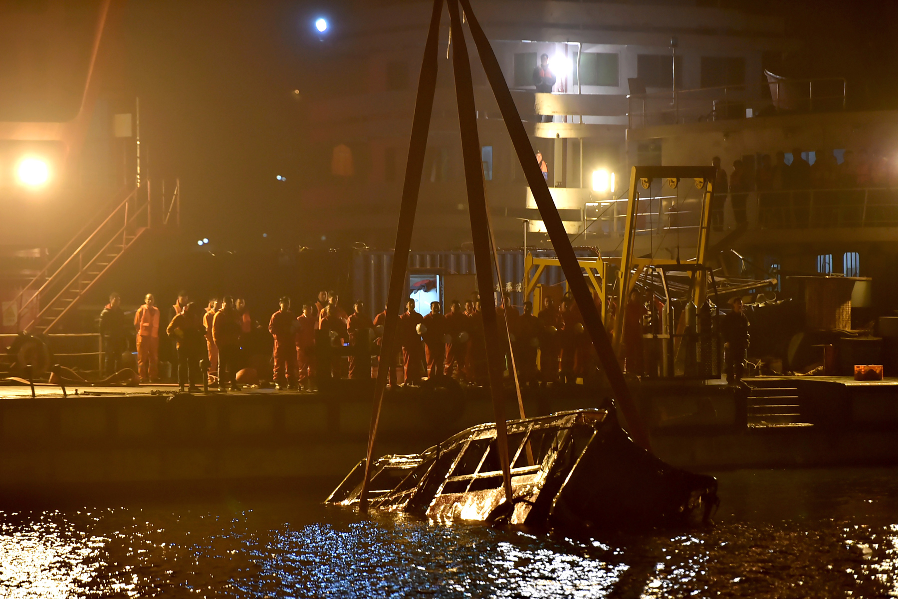 Rescuers watch as wreckage of a bus is lifted out of the Yangtze River in Wanzhou, Chongqing, October 31. The bus crashed and plunged into the river, leaving no survivors. A video released by the police shows that a passenger attacked the driver after she missed her stop and the driver refused to let her off halfway. The driver fought back and lost control of the bus. All 15 people, including the passenger and driver, died in the crash. (Chinatopix via AP Photo)