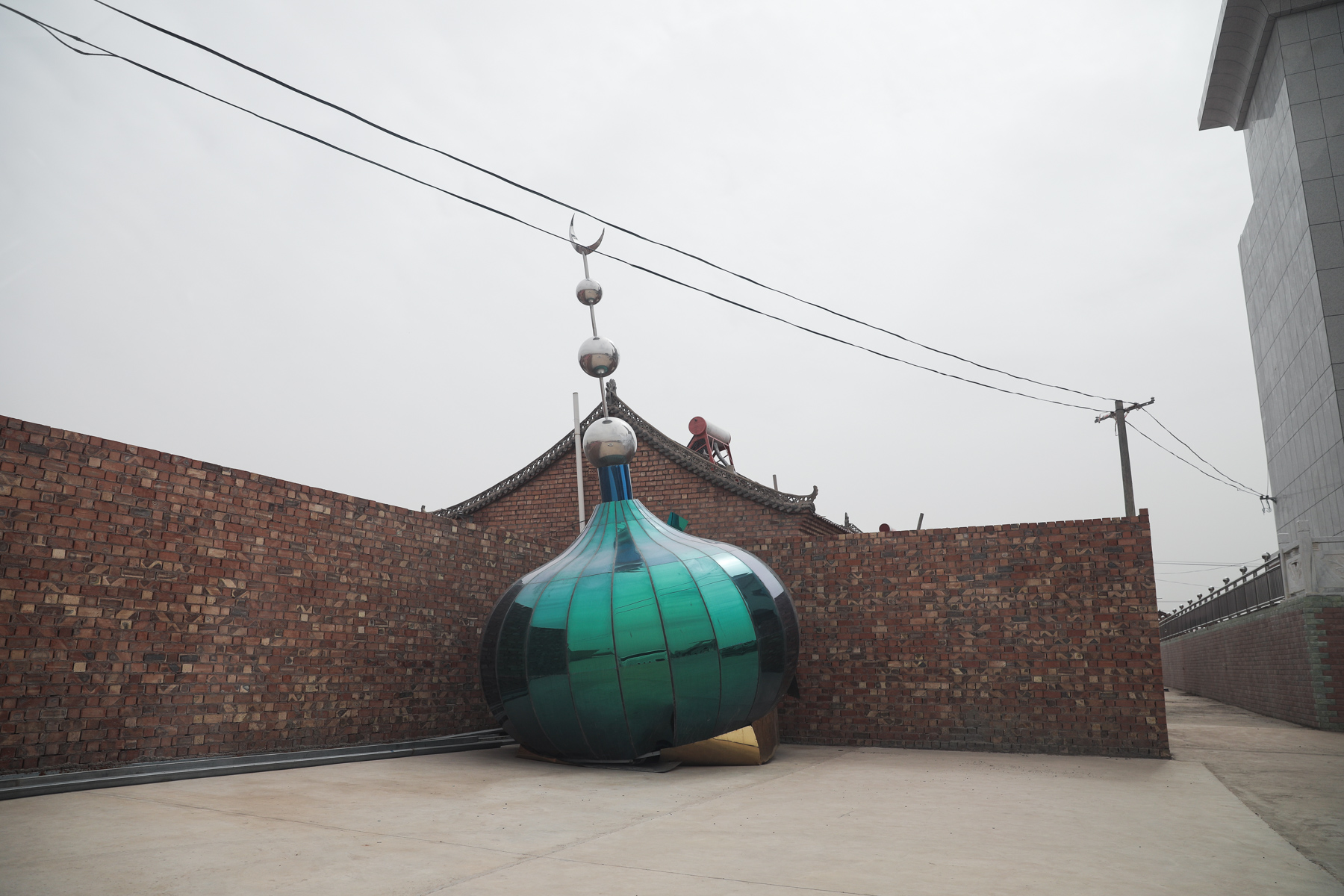 A green dome topped with a silver crescent moon rests on the ground after being removed from a mosque in Tongxin county, Ningxia Hui Autonomous Region, May 26. As China’s government has escalated its campaign of repression of Muslim ethnic minorities in Xinjiang, China’s Hui Muslims, who live throughout China, have also begun to face new constraints on their religious practice. Local authorities have started to “transform” Islamic architecture, stripping it of its defining characteristics. (DW News)    