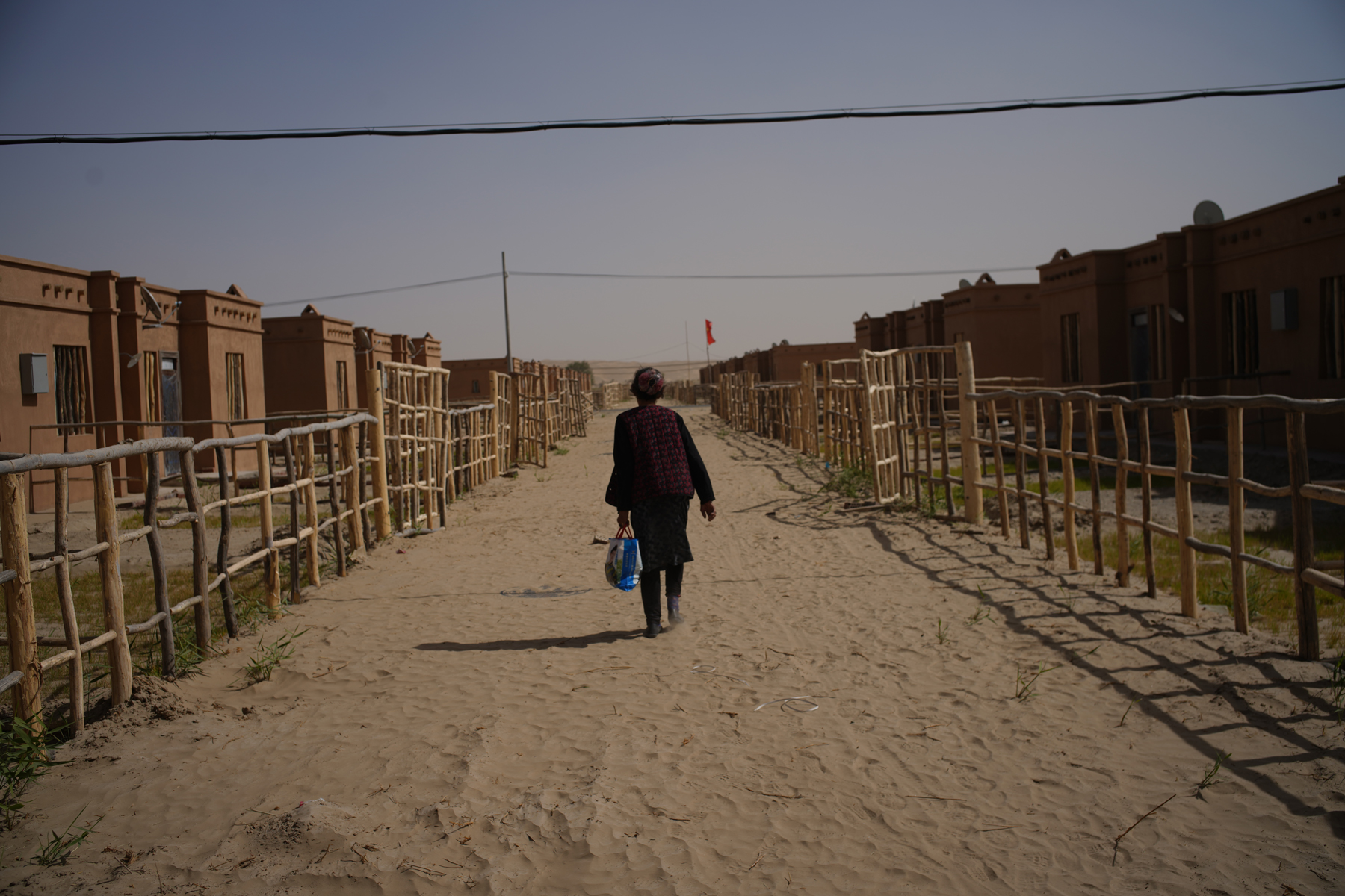 A Uighur woman walks through a new town constructed to house people relocated from a remote village, as part of a national poverty alleviation program, in Xinjiang Uighur Autonomous Region, October 4. Authorities in Xinjiang have incarcerated some one million Uighurs as part of a campaign of religious and cultural repression China’s government construes as a method for preventing terrorism. (Chen Jie for ChinaFile)