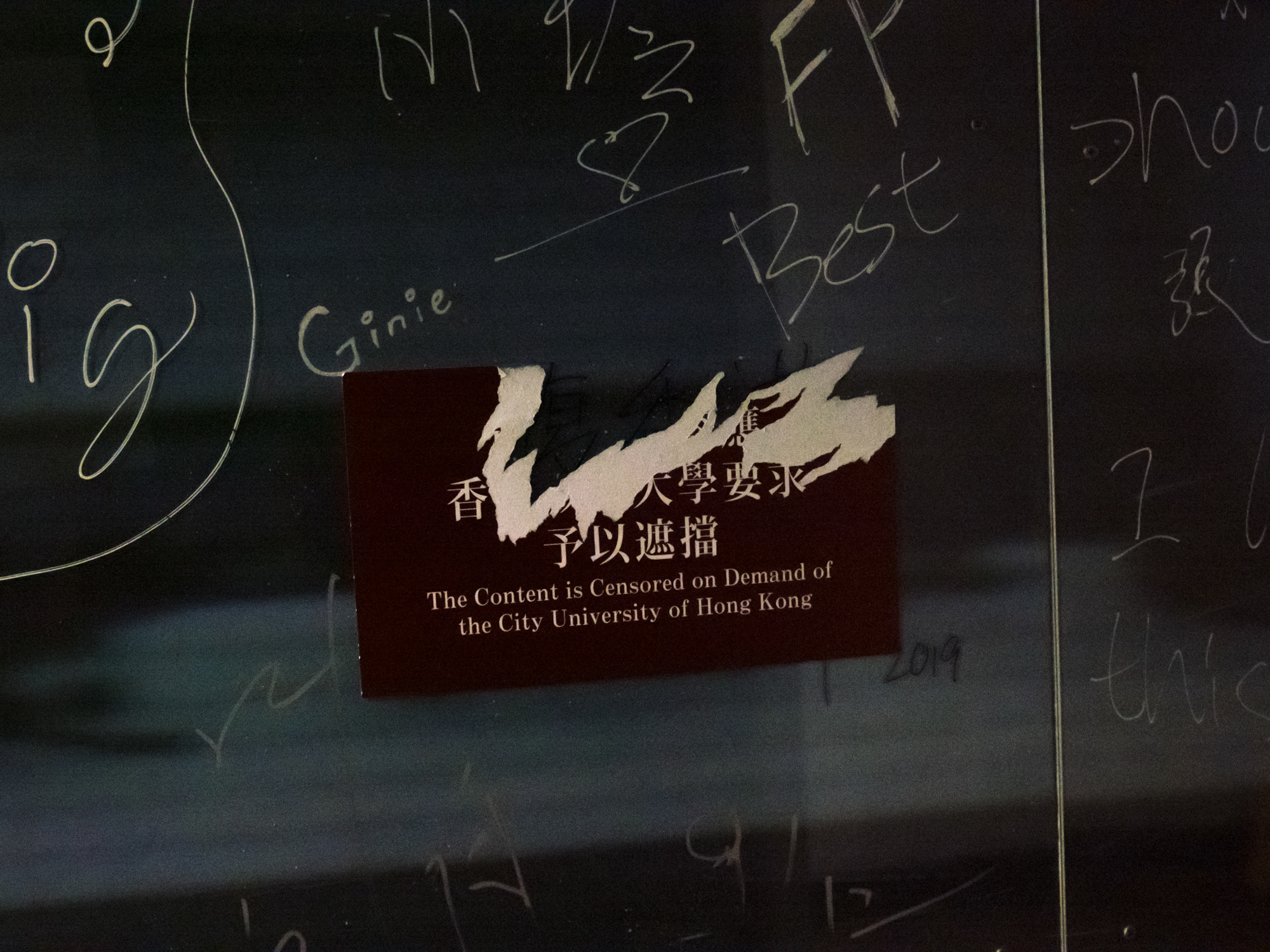 A sticker conceals a political slogan written on the glass window on the City University of Hong Kong campus, August, 2022.