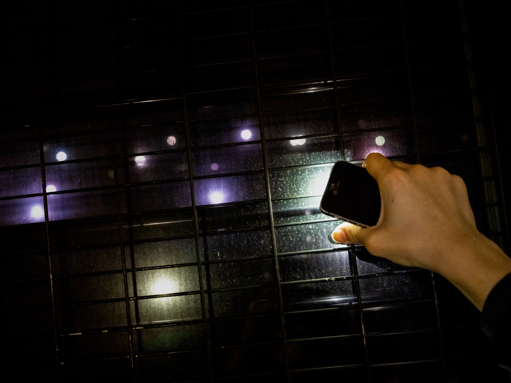 Supporters of individuals sentenced under the National Security Law for “rioting” stand outside a Magistrates’ court, pointing the flashlights on their mobile phones at the departing prison van, June 2022.